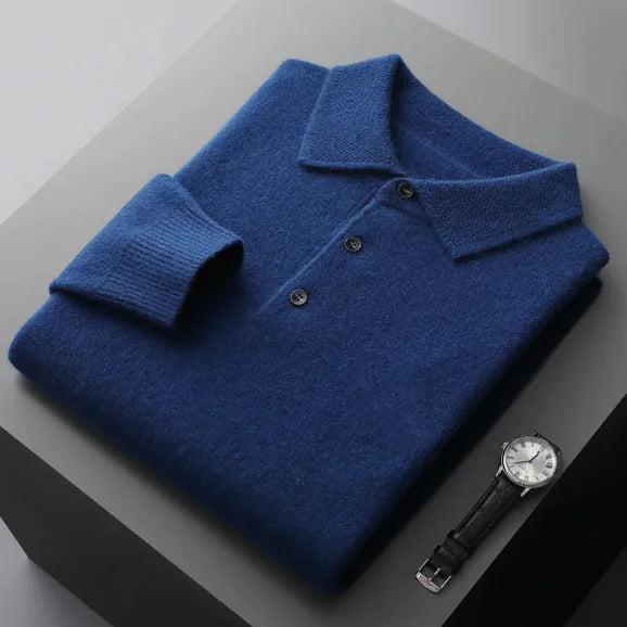 Folded blue sweater on a gray surface with a watch beside it