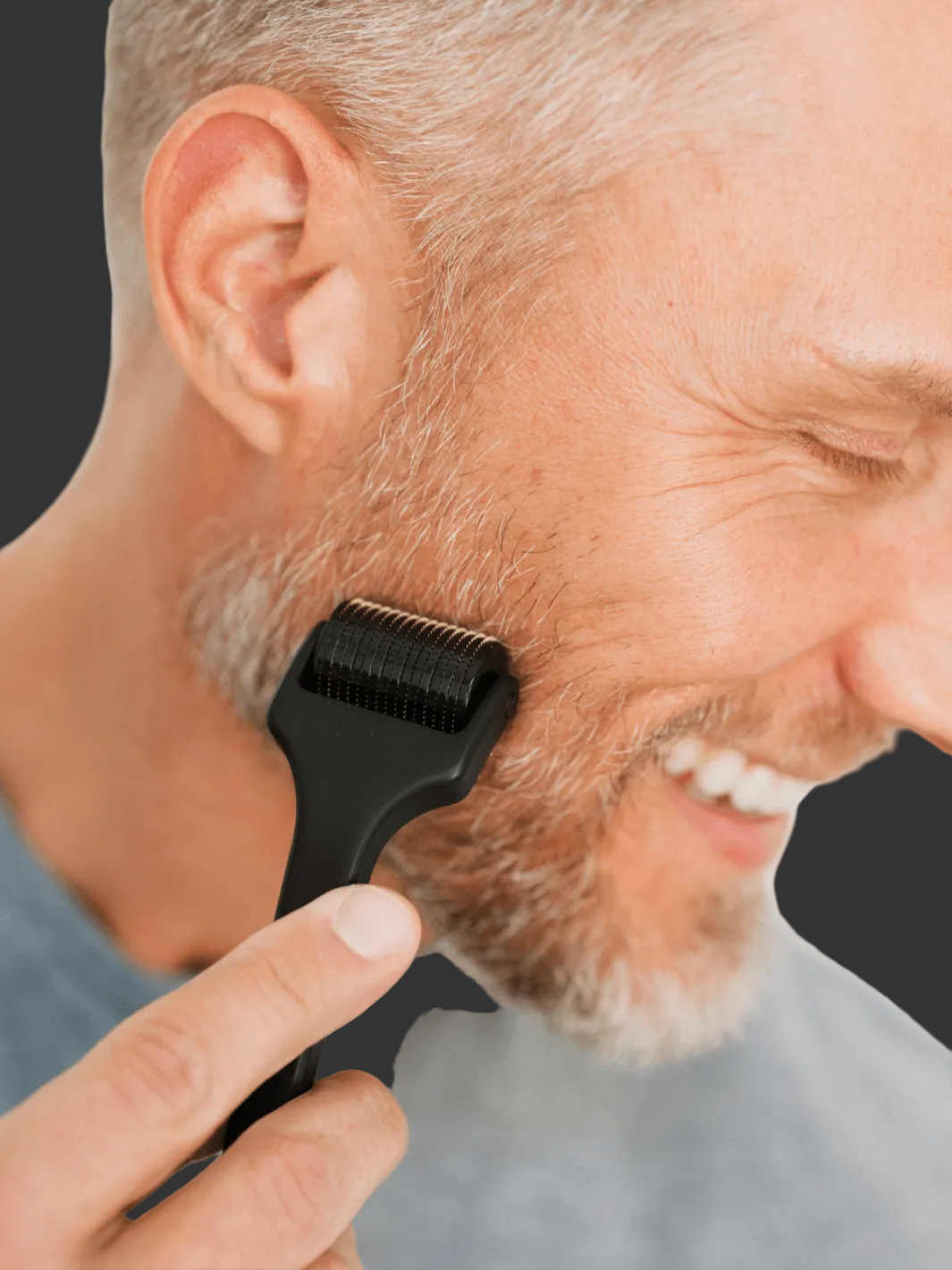 Man using black Beard roller on face with a blurred white background.