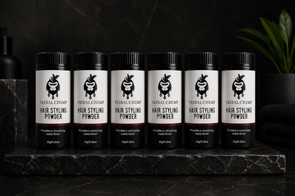 Row of Tribal Chimp hair styling powder bottles on a dark surface with a black background.